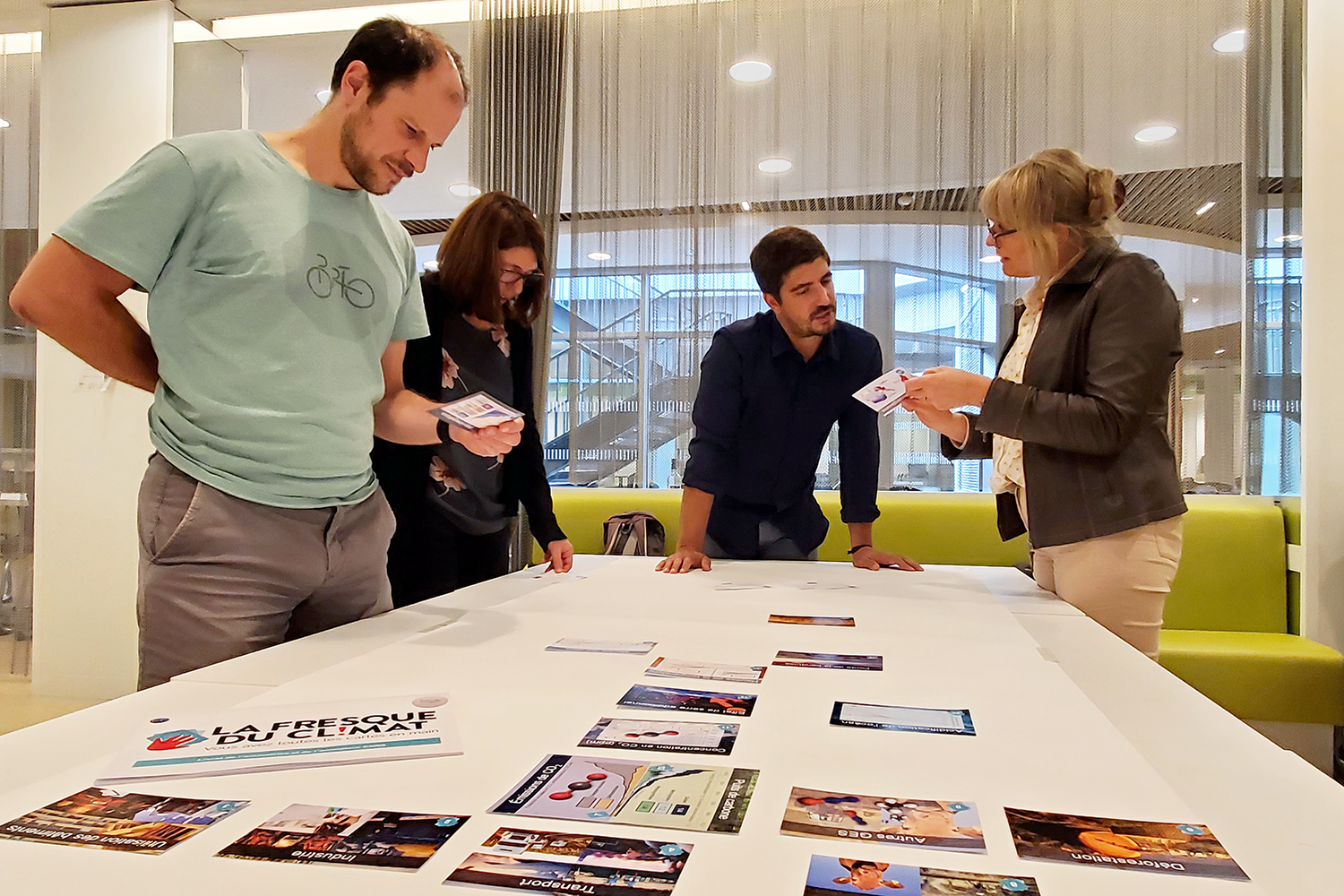 Plusieurs personnes réfléchissant debout autour d'une table sur laquelle se trouve des cartes de la fresque du climat