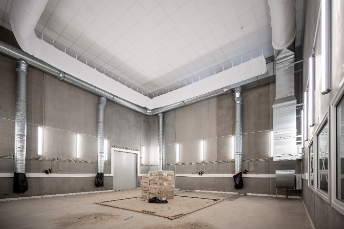 Grande salle vide en cours d'aménagement, on voit que des appareils sont installés au plafond, au sol et sur les murs