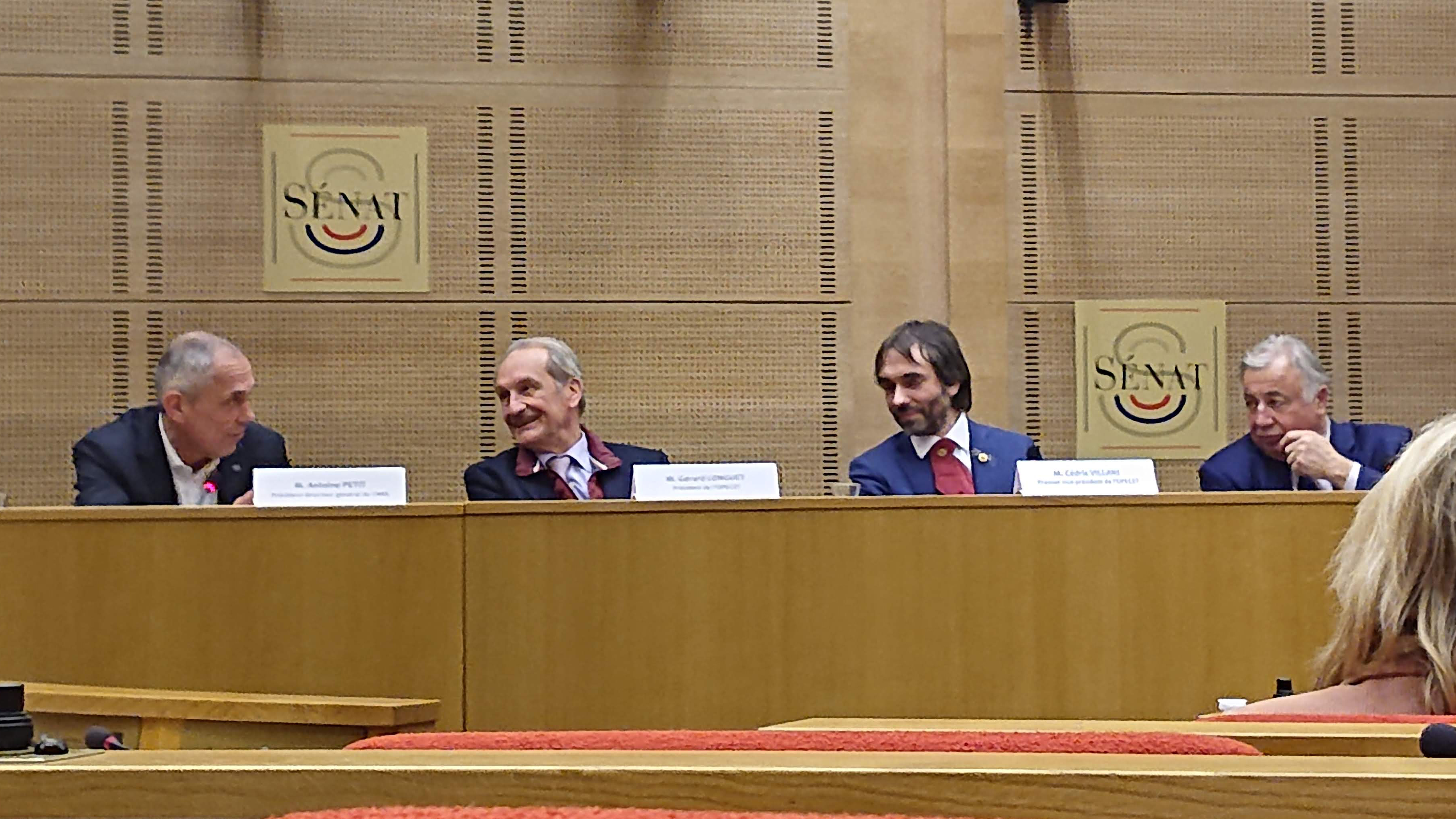 MM. Petit, Longuet, Villani et Larcher sur une estrade dans une salle du Sénat