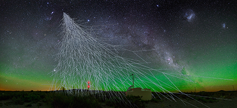 Vue d'artiste d'une gerbe atmosphérique au-dessus d'un détecteur de particules de l'Observatoire Pierre Auger, sur fond de ciel étoilé.