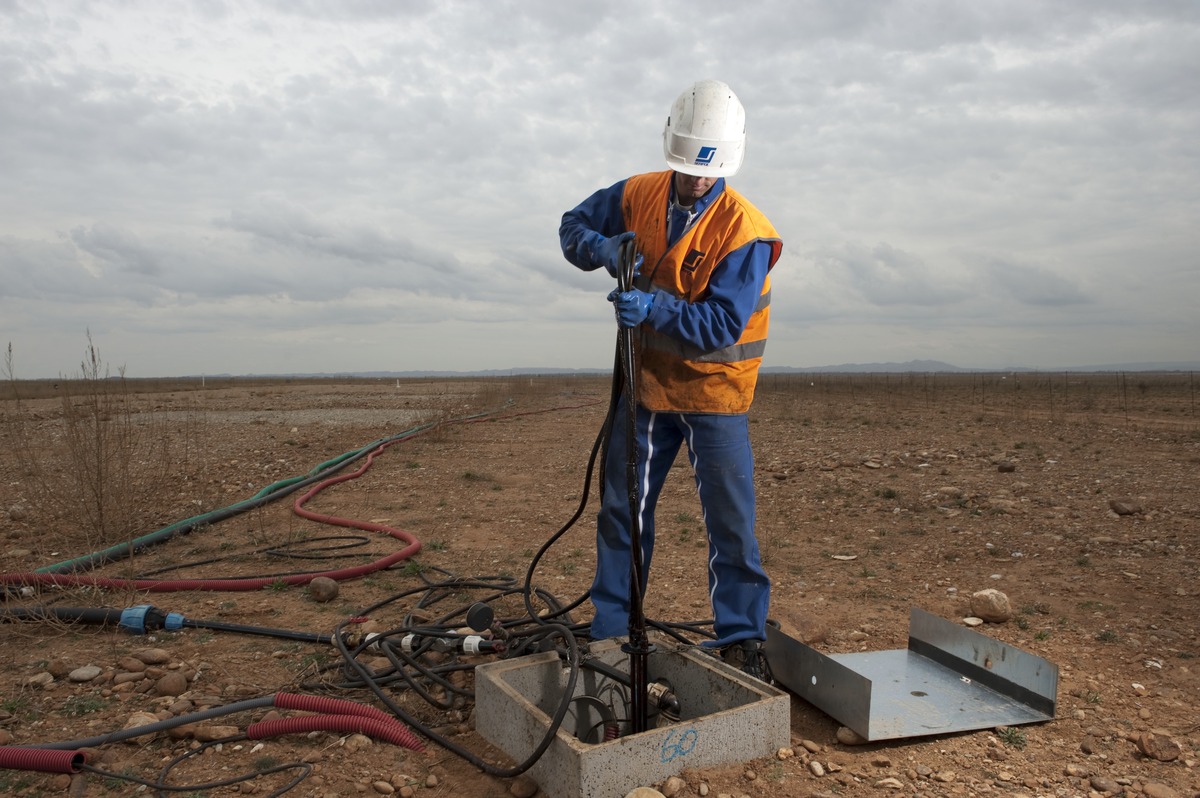 Un technicien sort une pompe d'un puits de captage d'eau, sur le site du chantier de réhabilitation